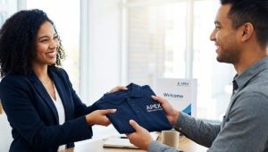 New employee receiving custom embroidered polo shirt during onboarding representing professional first impressions with employee uniforms for small business